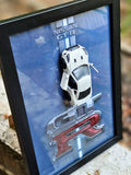 Nissan GT-R pearl white die-cast model in black shadow box with blue GT-R Performance Series backdrop